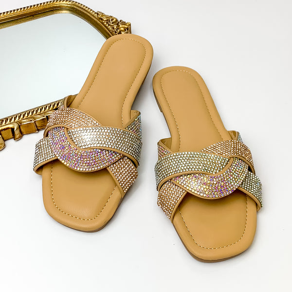 Tan sandals with three crystal bands overlapping for the strap. Each bands has a different color crystal including one clear crystal, one ab crystal, and one champagne crystal band. These sandals are pictured on a white background with a gold mirror in the top left corner.