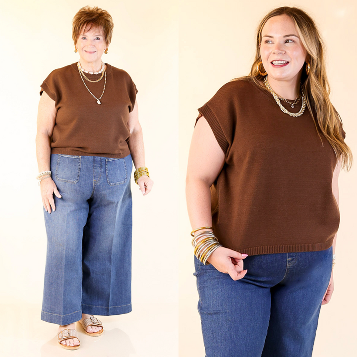 Two women wearing brown tops and blue jeans against a plain background