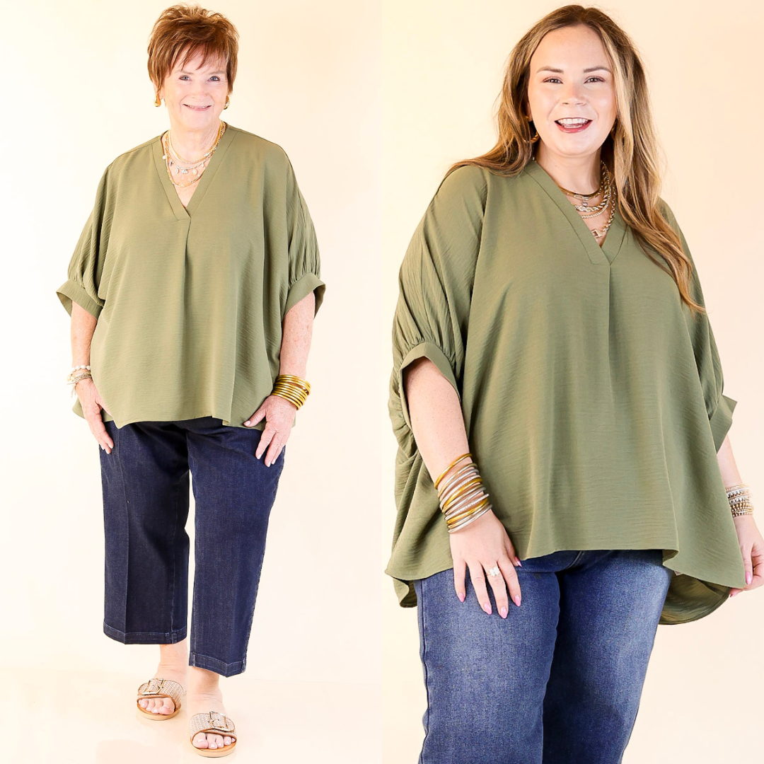 Two women wearing olive green tops and blue jeans on a beige background