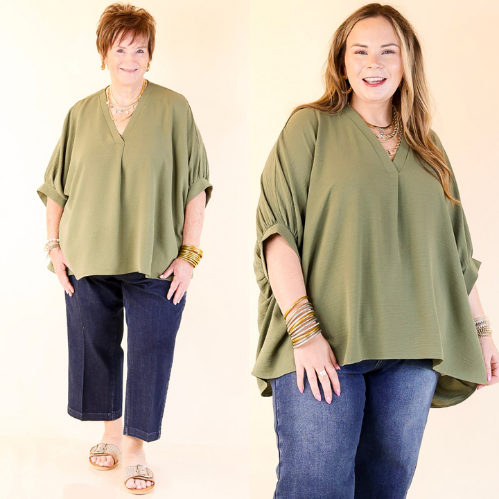 Two women wearing olive green tops and blue jeans on a beige background