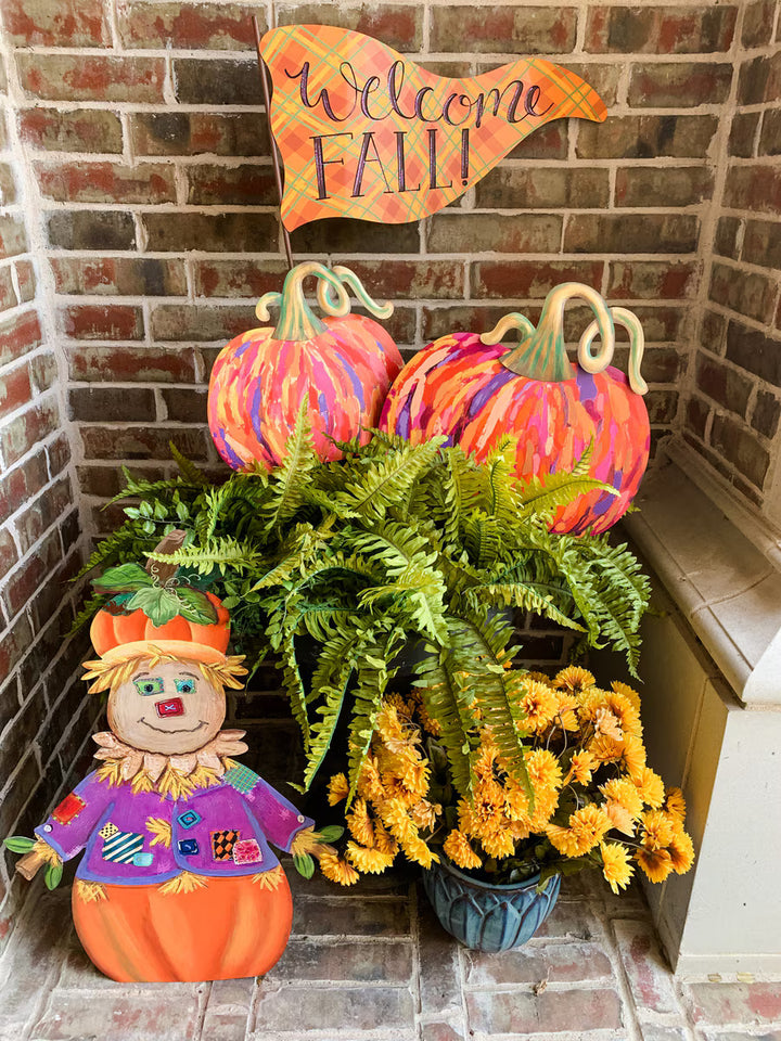 Colorful Artful Pumpkins by The Round Top Collection styled on a fall front porch with green ferns and Halloween garden stakes.