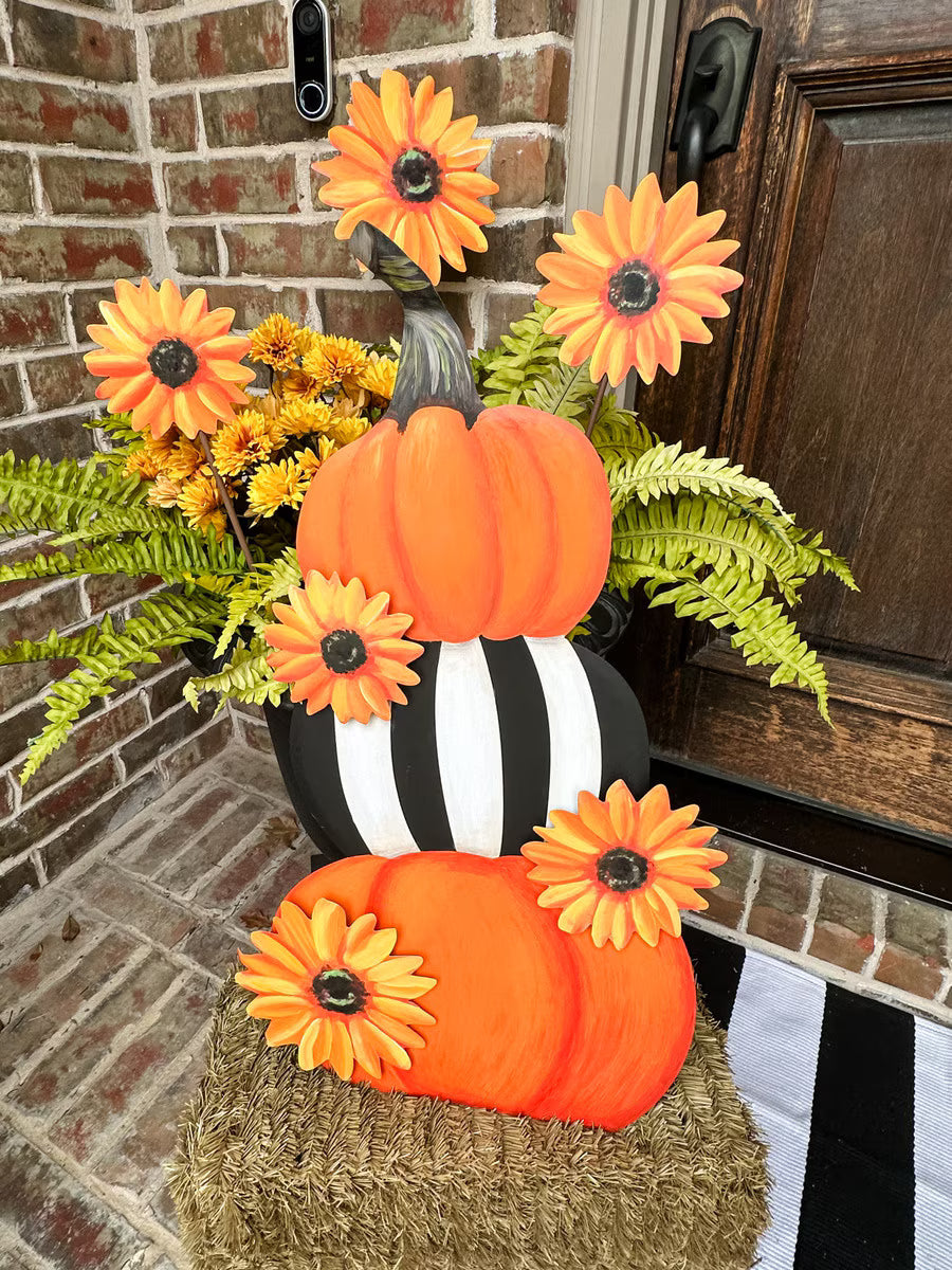 Round Top Collection Pumpkin and Sunflower Stack styled on a hay bale with orange sunflower stakes, mums and ferns for fall porch decor.