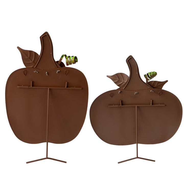 Back of two brown metal pumpkin-shaped stands on a white background