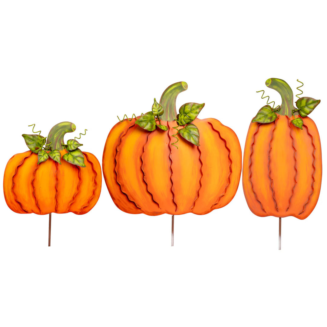 Three decorative pumpkins on stakes with green stems against a white background