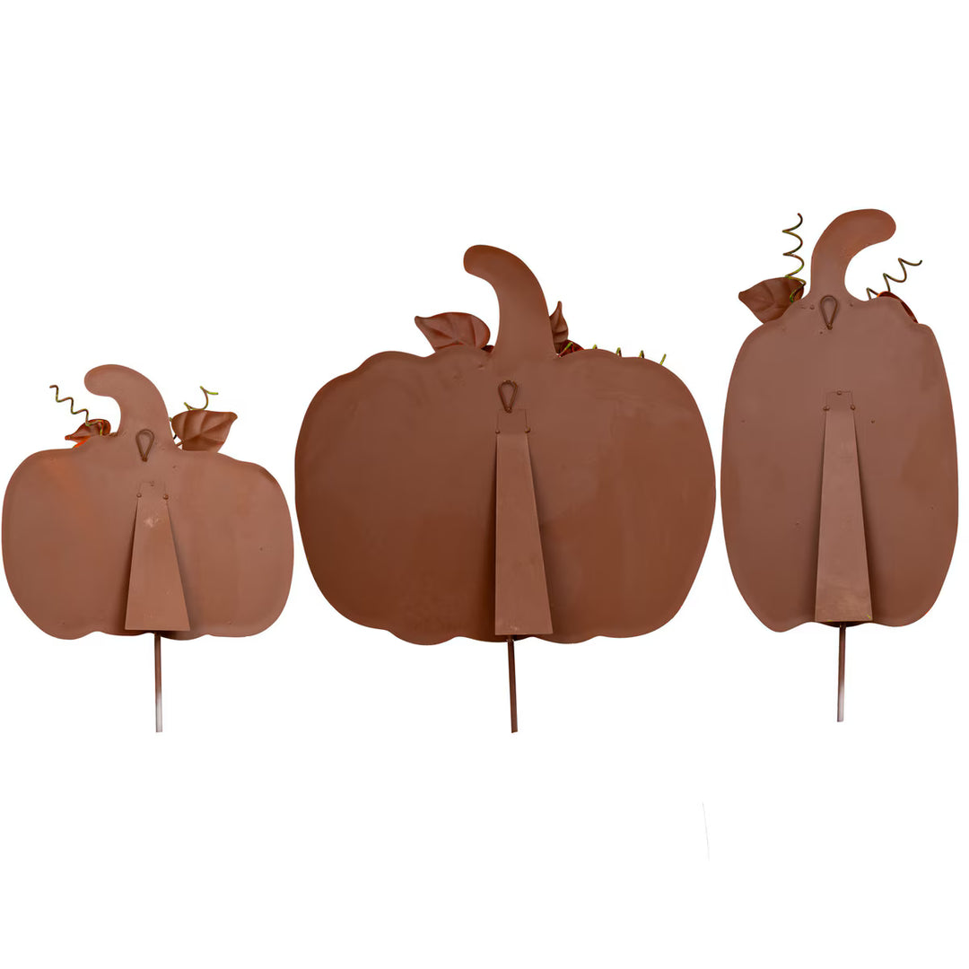 Three brown pumpkin decorations on sticks against a white background