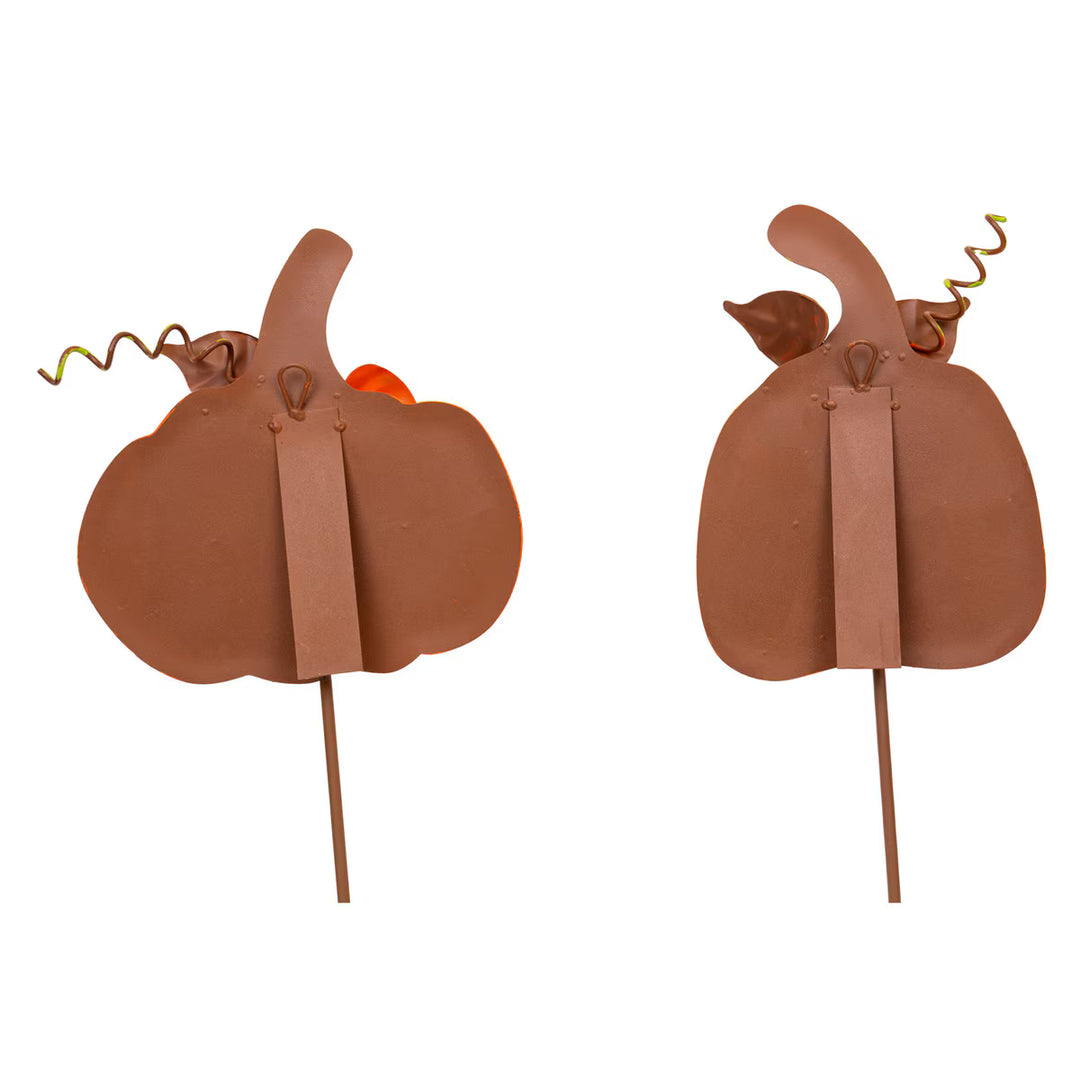 Back side of two decorative pumpkins on sticks with stems on a white background