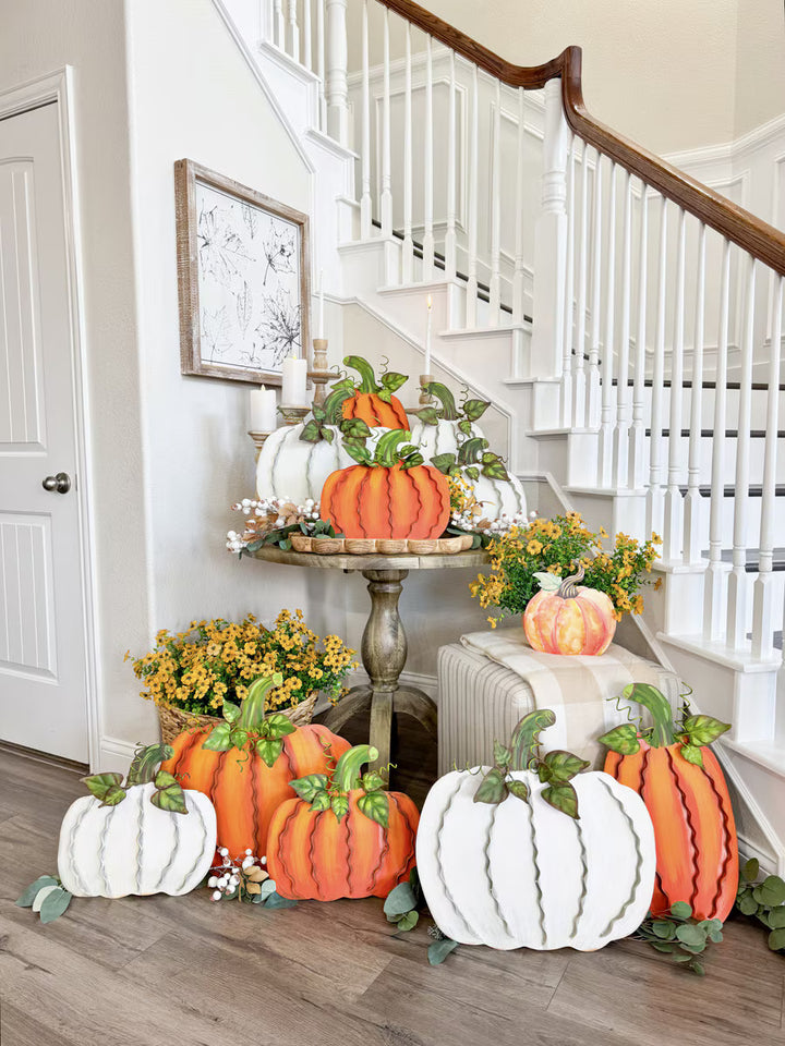Round Top Collection cream and orange Ribbon Pumpkins arranged in a layered fall entryway display with greenery and autumn flowers.