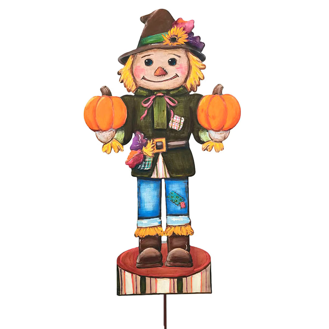 Large Scarecrow Nutcracker by Round Top Collection holding two orange pumpkins with green jacket, blue pants, fall hat and striped base.