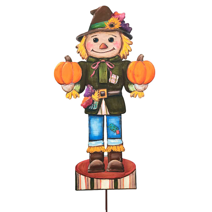 Large Scarecrow Nutcracker by Round Top Collection holding two orange pumpkins with green jacket, blue pants, fall hat and striped base.