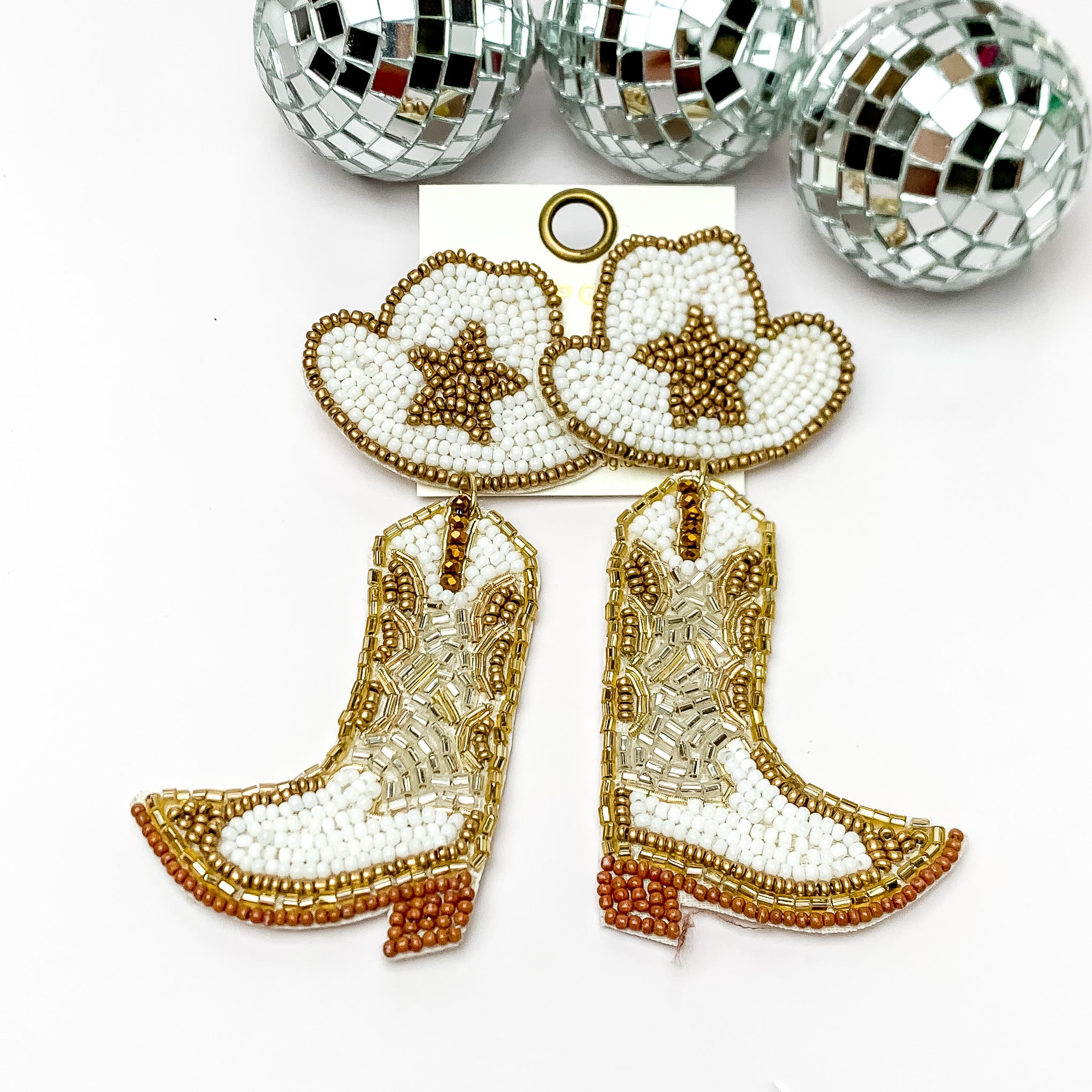 Beaded White, and Gold Cowboy Boot Earrings with Hat Studs. Pictured on a white background with disco balls at the top.