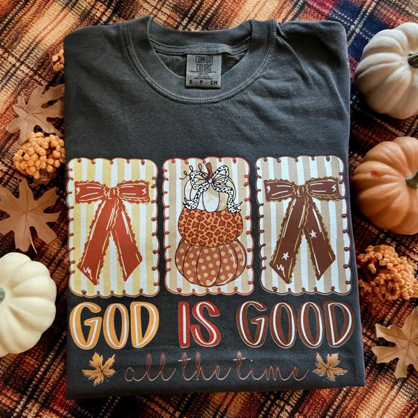 Folded t-shirt with 'God is Good all the time' text and pumpkins on a fall-themed background.