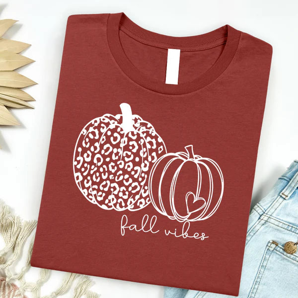 Maroon t-shirt with white pumpkin design and 'fall vibes' text on a light background