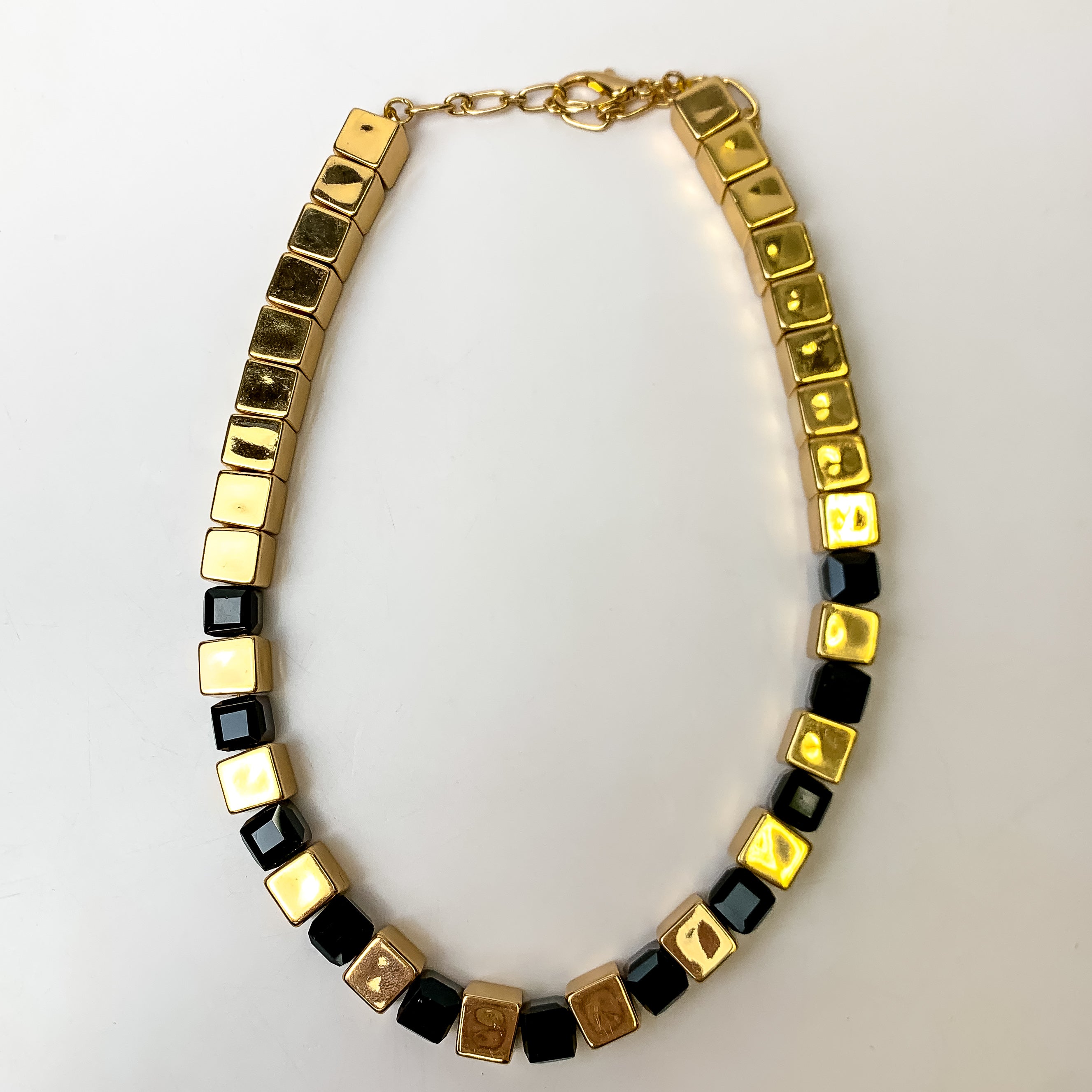 This Fashionably Late Gold Toned Cubed Necklace in Black is pictured on a white background.