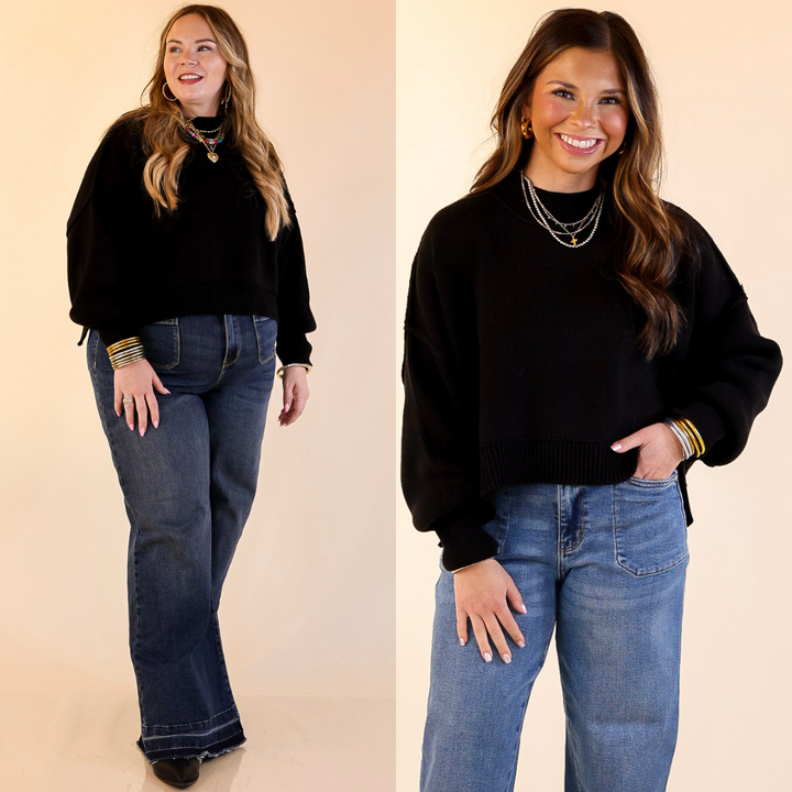 Two models wearing the Black 'Fireside Fit' cropped long sleeve mock neck sweater with jeans. Against a plain background.