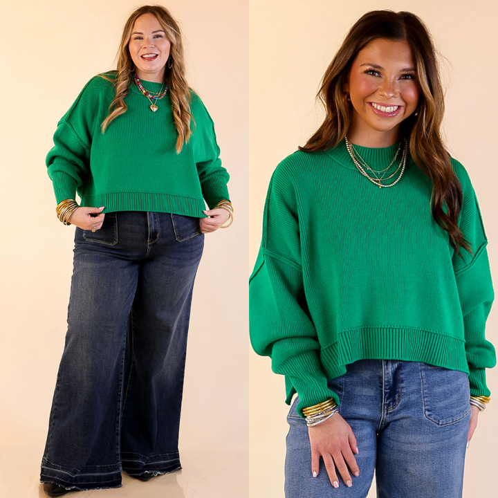 Two models wearing the Kelly Green 'Fireside Fit' cropped long sleeve mock neck sweater with jeans. Against a plain background.