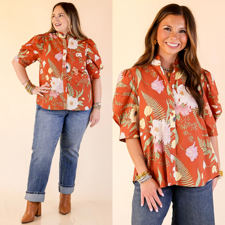 Women wearing button up puff sleeve floral print top in rust orange against a plain background. 