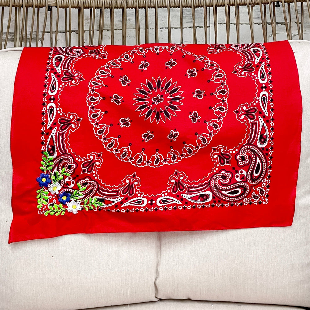 Red bandana with a floral design on a white cushion in a wicker chair.