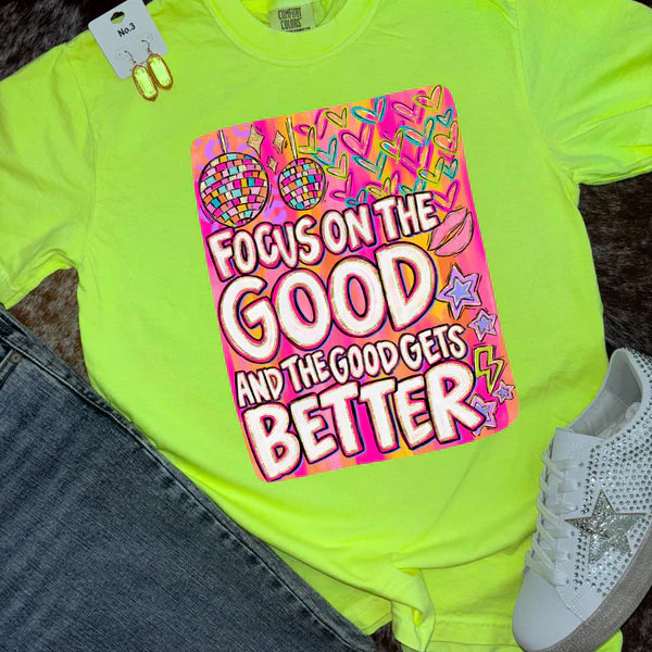 Neon green t-shirt with motivational quote graphic, jeans, and white sneakers on a dark surface.