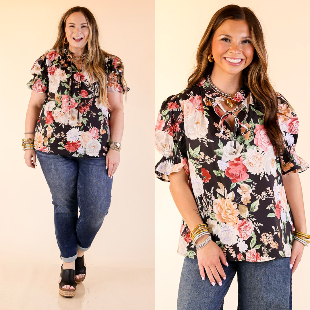 Models wearing floral print top with short puff sleeves in black against a plain background. 