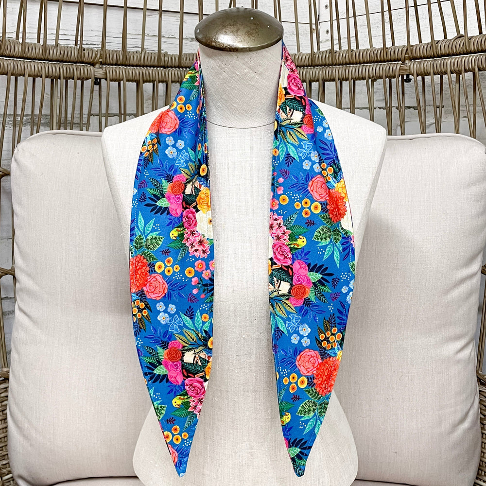 Mannequin wearing a colorful floral scarf on a white cushioned chair with wicker backrest.