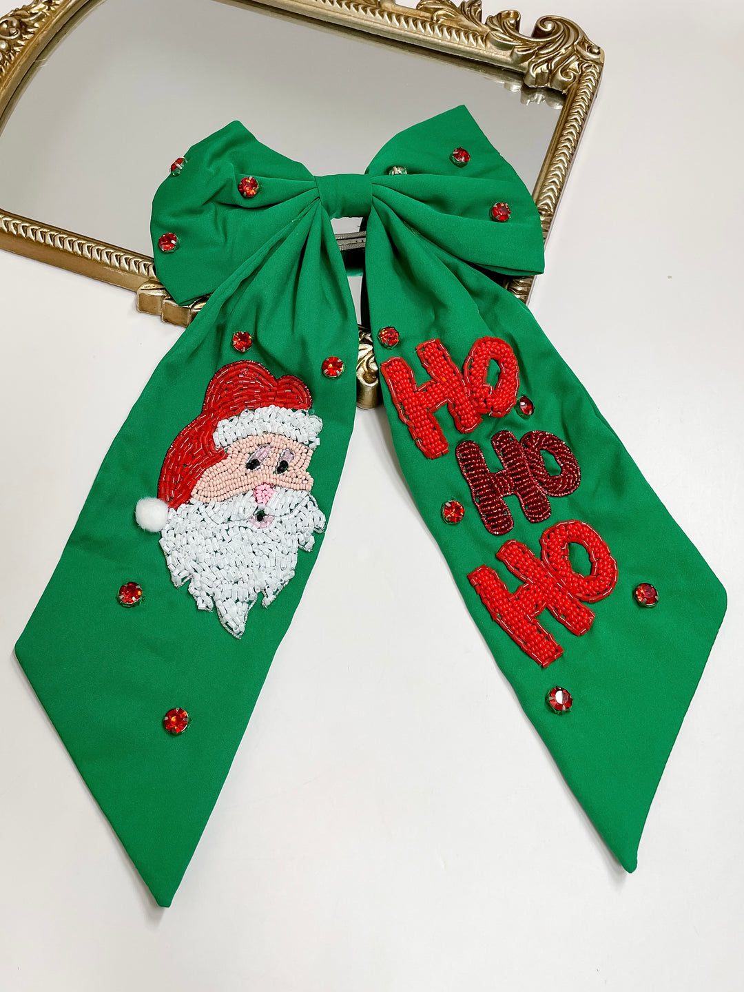 Green hair bow with hand-beaded Santa face and “HO HO HO” design, red crystal accents, festive holiday accessory.