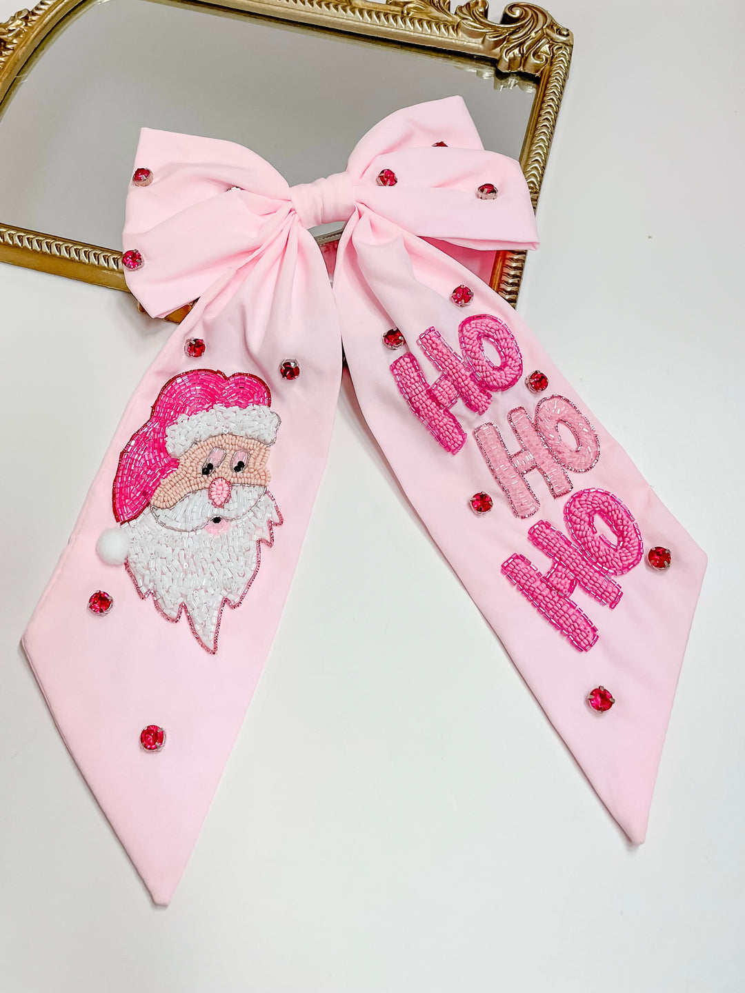 Pink Christmas hair bow with beaded Santa face and pink “HO HO HO” lettering, embellished with red crystals.