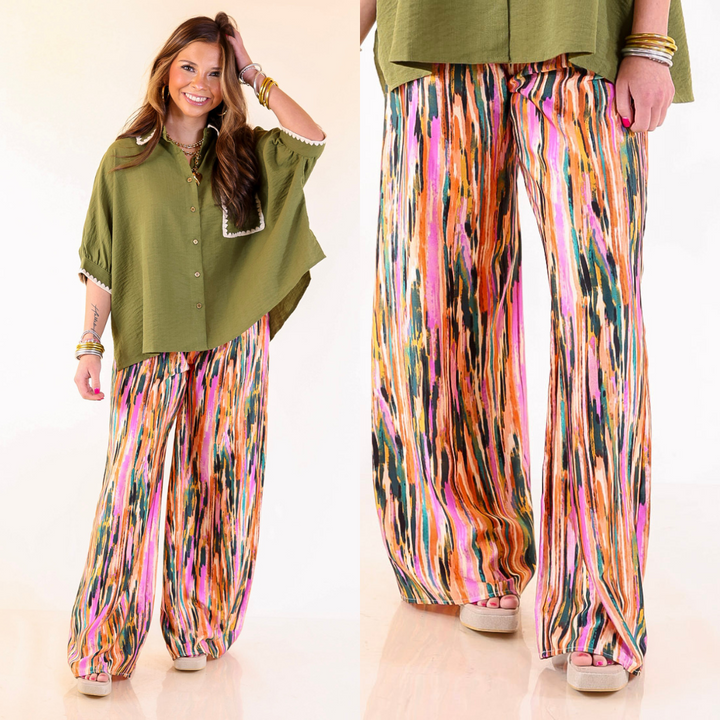 Woman wearing a green top and colorful wide-leg pants on a beige background