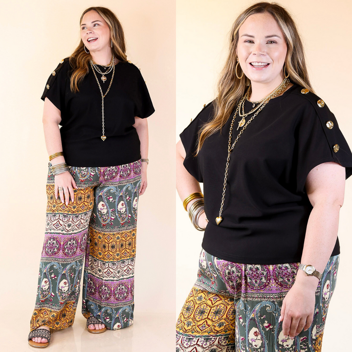Woman wearing a black top with gold buttons and patterned pants on a beige background