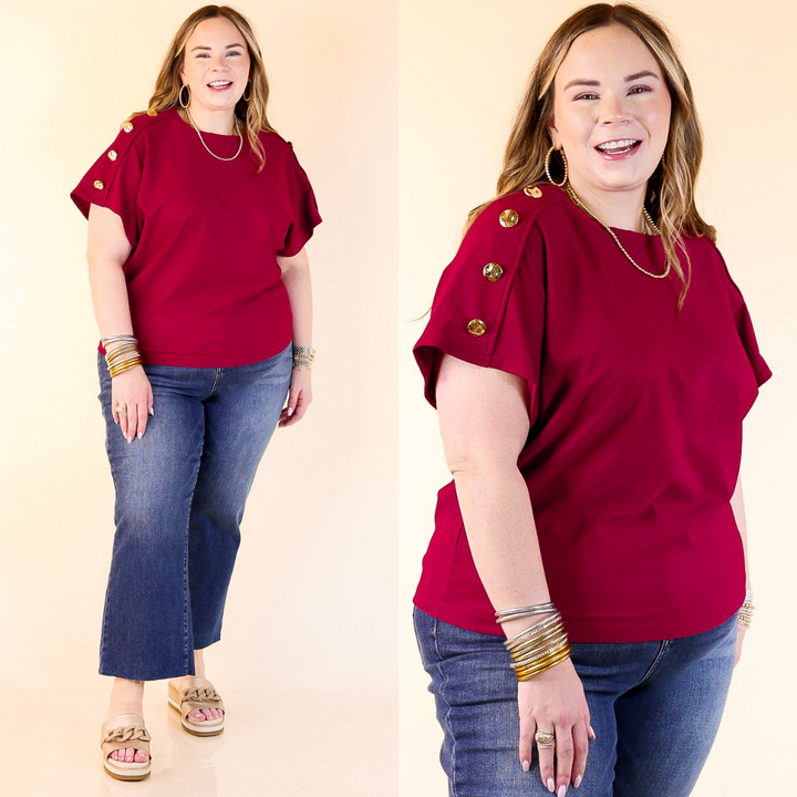 Woman wearing a Maroon with gold buttons and blue jeans on a beige background