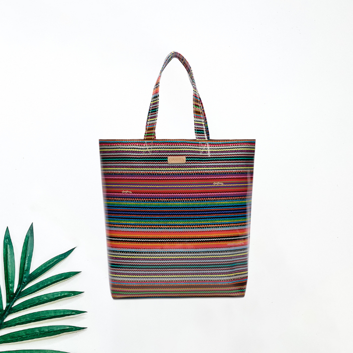 Multicolored striped tote bag on a white background with a green leaf