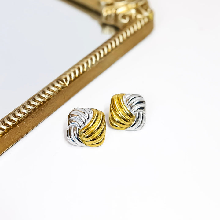 Pair of gold and silver earrings on a white background with a decorative gold frame.