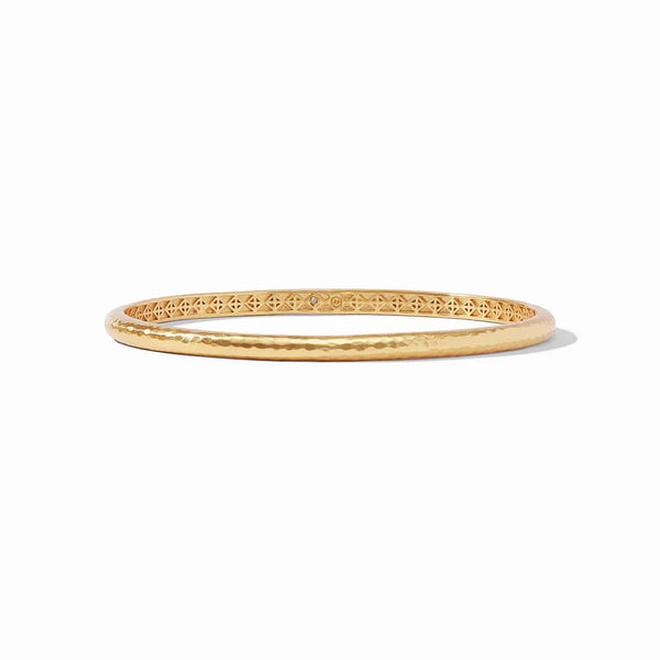 Pictured is a gold, hammered bangle pictured on a white background. 