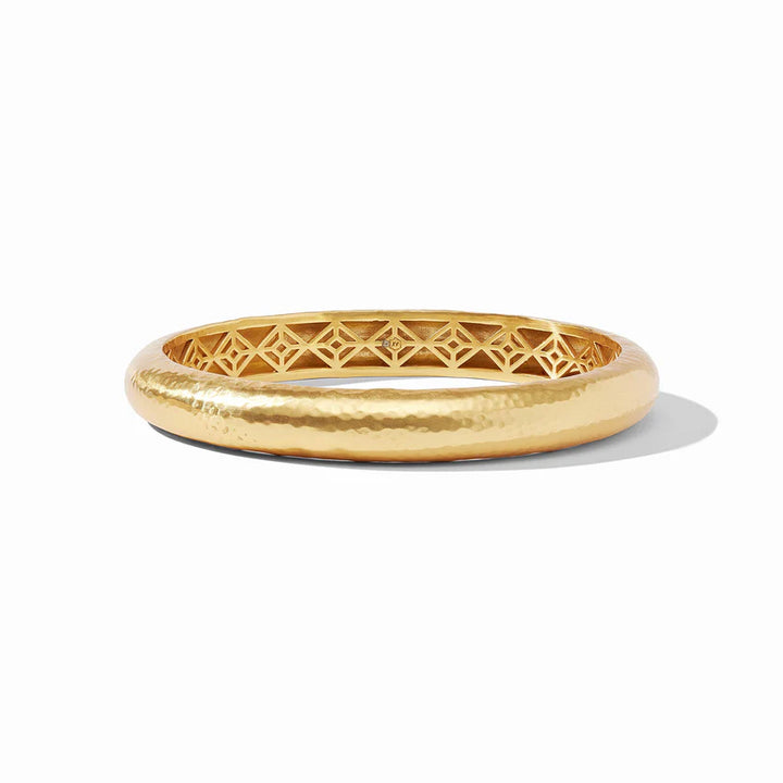 Pictured is a gold, hammered bangle pictured on a white background. 