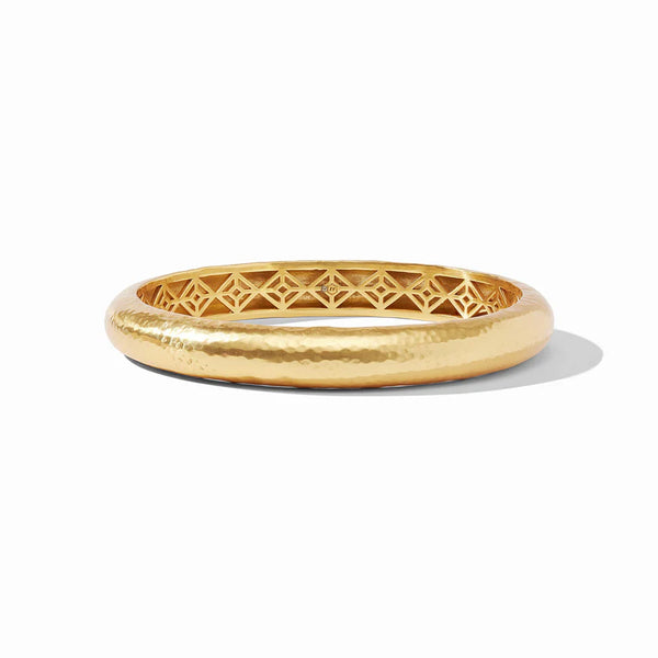 Pictured is a gold, hammered bangle pictured on a white background. 