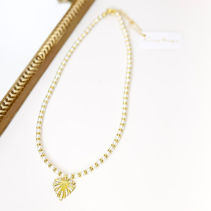 Gold necklace with a heart pendant on a white background
