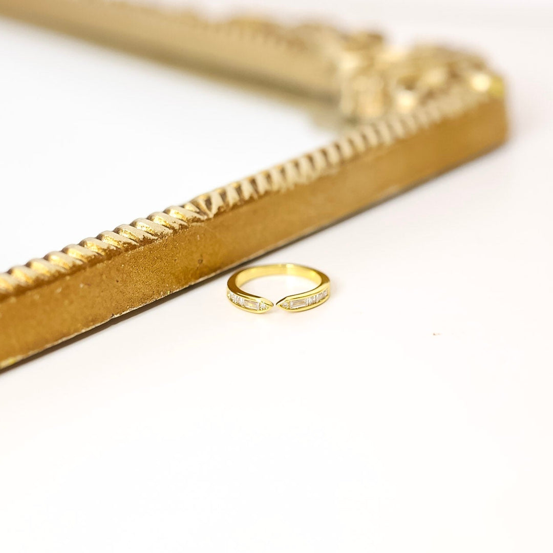 Gold ring on a white surface with a gold decorative object in the background