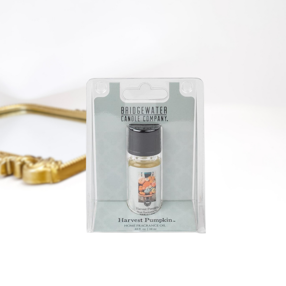 A solid white background with a gold mirror and a home fragrance oil by bridgewater candle company.