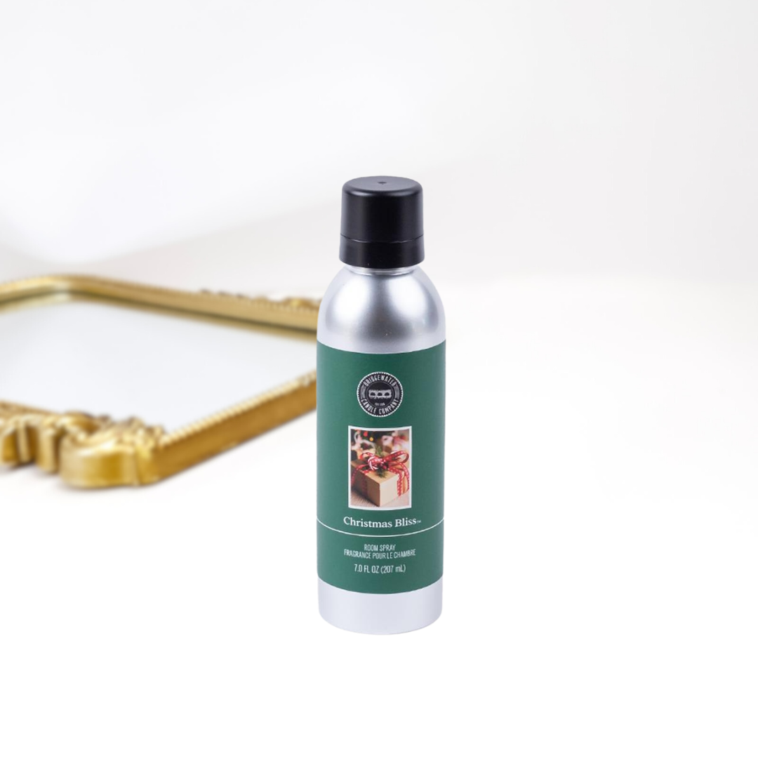 A solid white background with a gold mirror and a bottle of room spray in a silver and black container. Created by bridgewater.