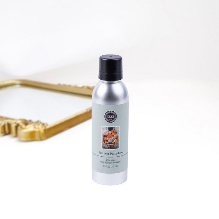 A solid white background with a gold mirror and a bottle of room spray in a silver and black container. Created by bridgewater.