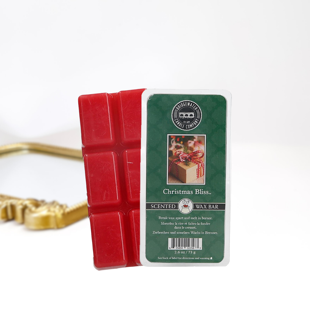 A solid white background with a gold mirror. In the front in a scented wax bar in scent christmas bliss