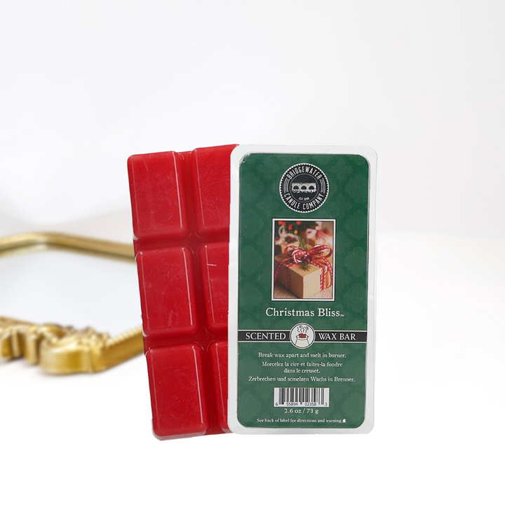 A solid white background with a gold mirror. In the front in a scented wax bar in scent christmas bliss