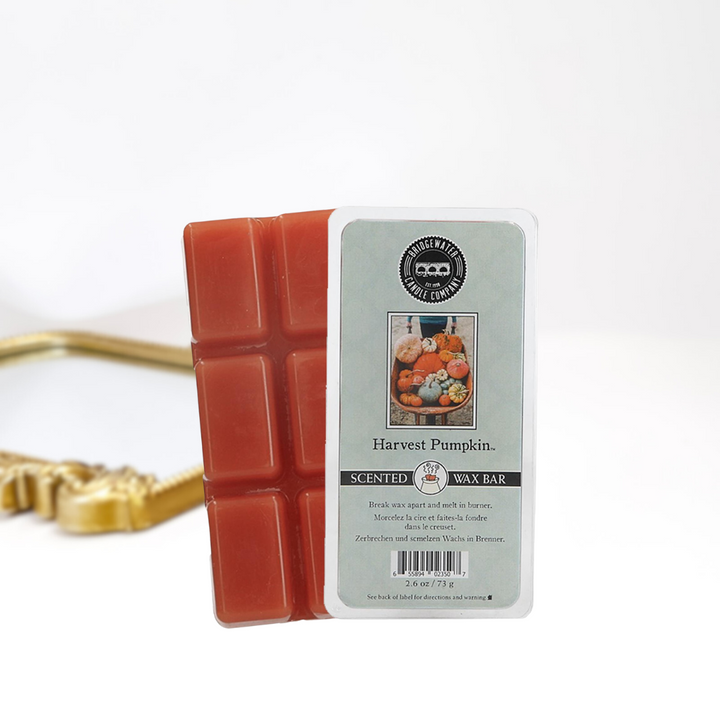 A solid white background with a gold mirror. In the front in a scented wax bar in scent harvest pumpkin.