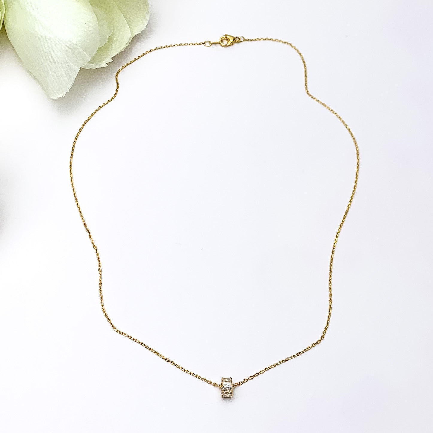 Gold Dipped Necklace With Clear Crystal Circle Charm. Pictured on a white background with a piece of wood behind the necklace.