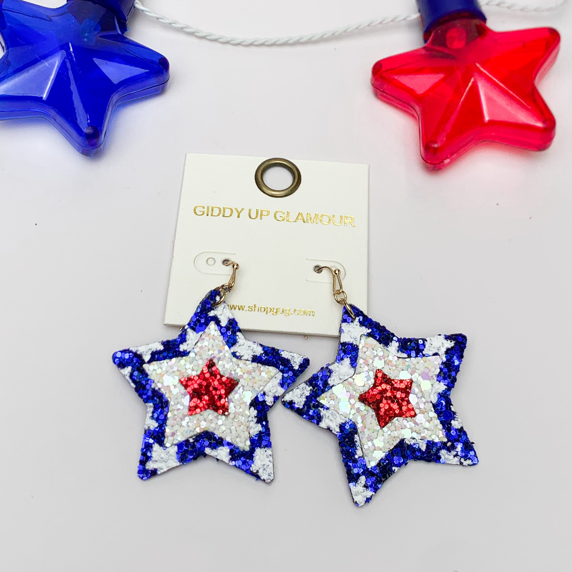 Patriotic Red, White, and Blue Star Earrings. Pictured on a white background with a blue and red star above the earrings for decoration. 