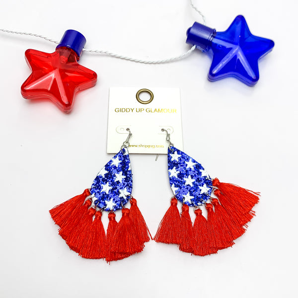 USA Blue Sparkly Teardrop Earrings With Red Tassels. Pictured on a white background with a red and blue star above the earrings.