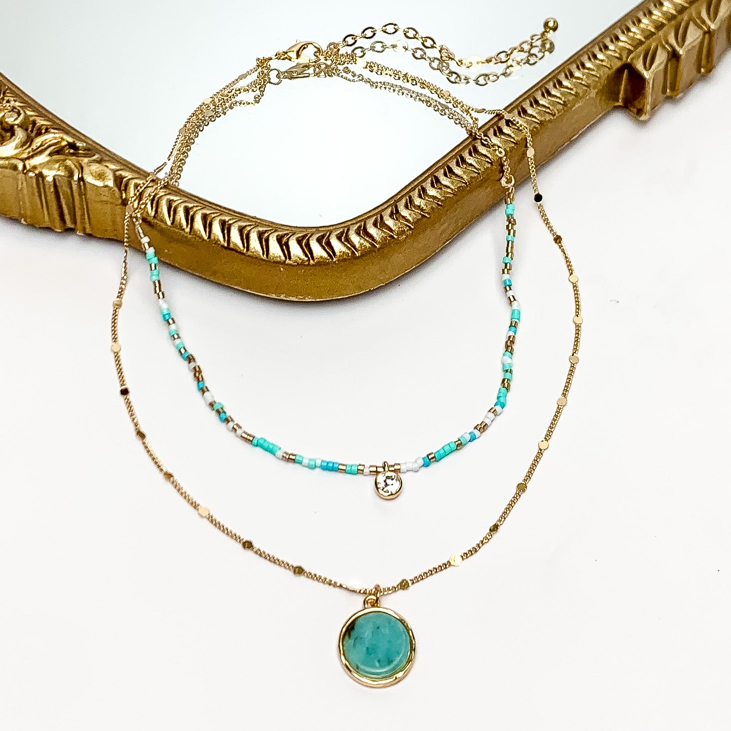 Turquoise Goddess Gold Tone Double Chain Necklace. Pictured on a white background with a mirror behind the necklace.