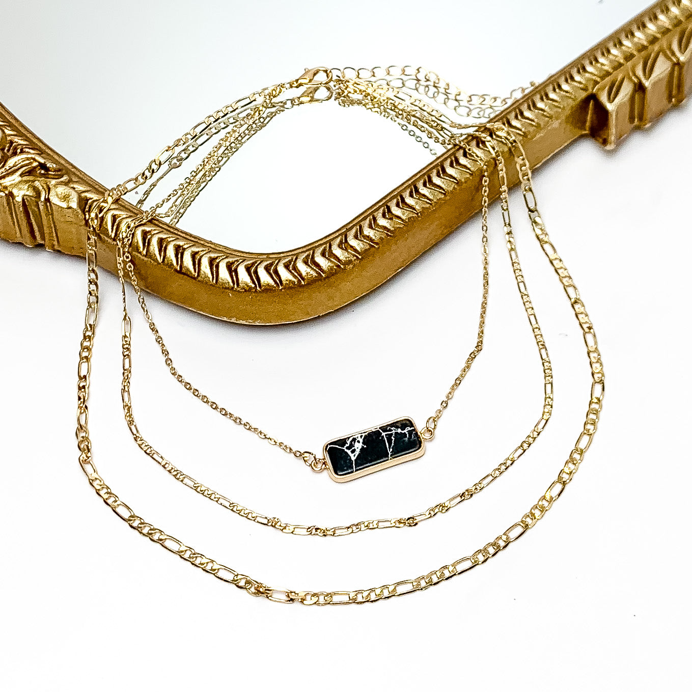 Black Stone Pendant Gold Tone Chain Three layered Necklace. Pictured on a white background with a mirror behind the necklace.