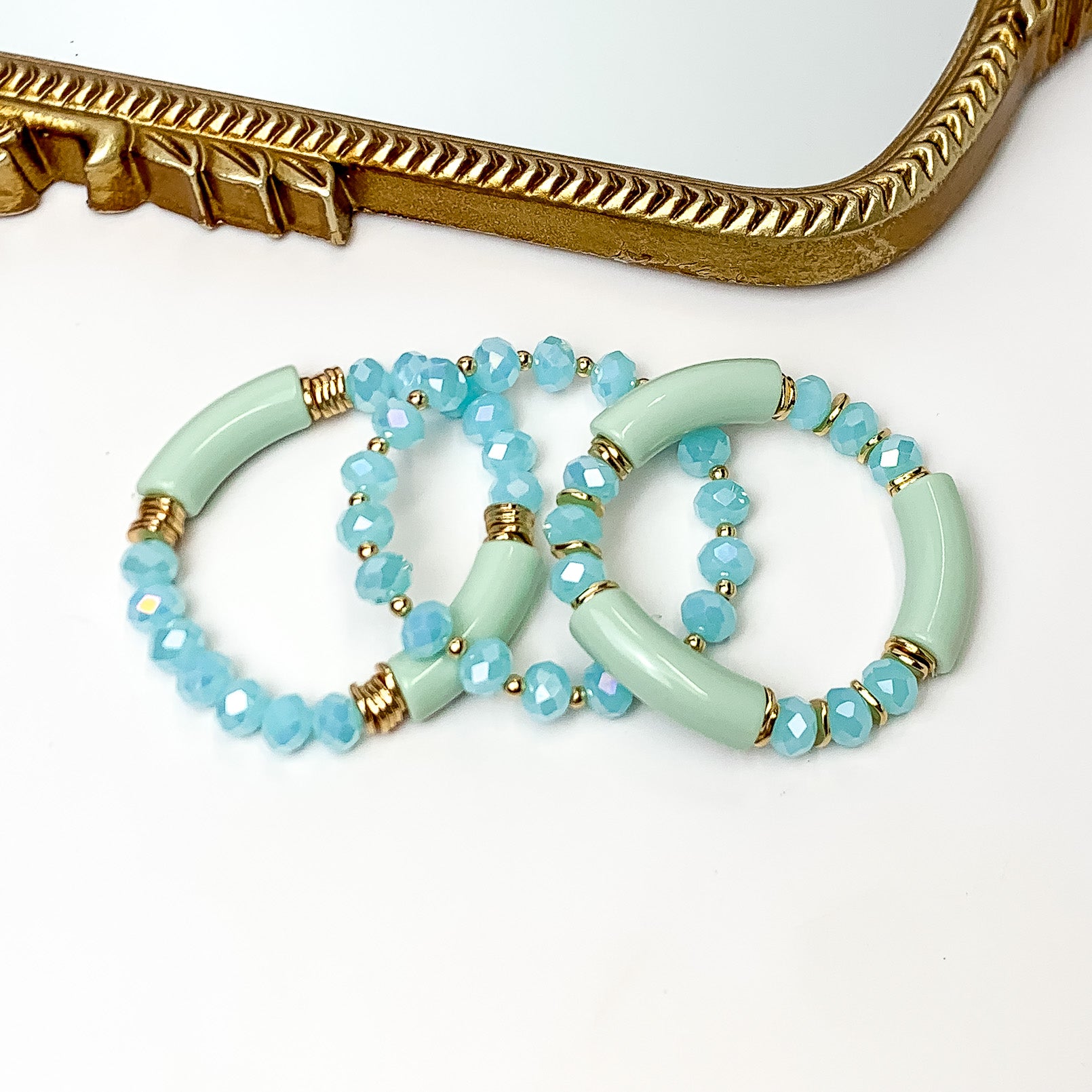 Set of Three | Sunny Bliss Crystal Beaded Bracelet Set in Light Blue. Pictured on a white background with a gold frame mirror at the top.