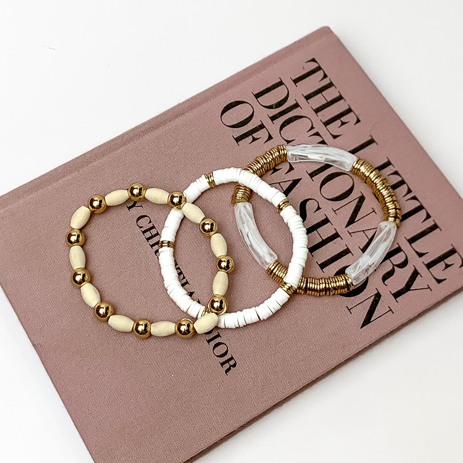 Set of Three | Goldie Goddess Tube and Beads Bracelet Set in White. Pictured on a white background with the bracelets laying on a book.