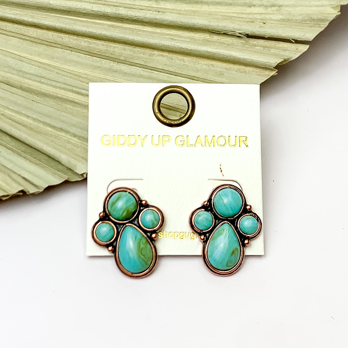 Copper Tone Cluster Stone Earrings in Turquoise Green. Pictured on a white background with a fan leaf behind the earrings.